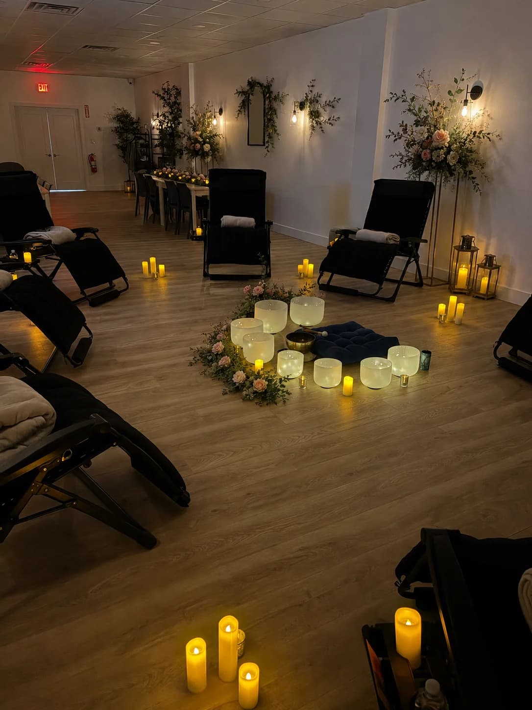 Candlelit sound bath setup with crystal singing bowls and reclining lounge chairs