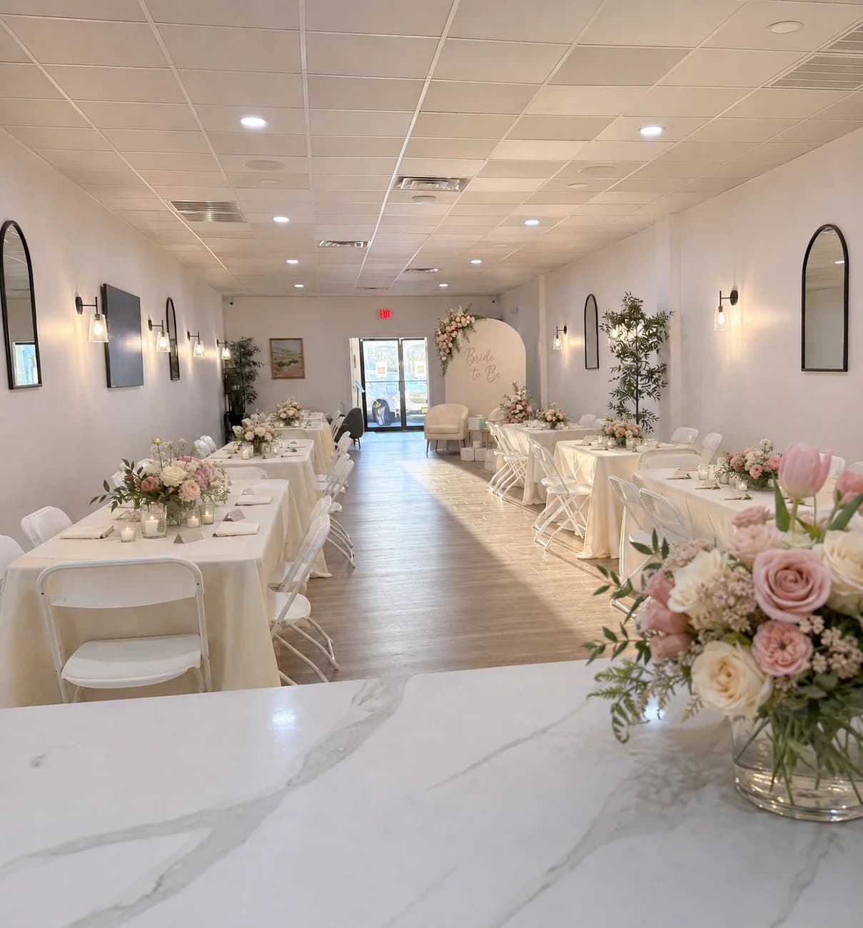 Bridal shower at Workshop with a white rose flower wall and long dinner tables