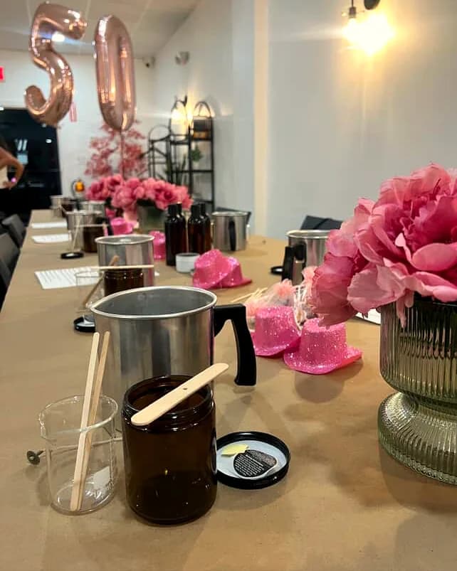 Candle-making station with wax pitchers and pink florals set for an adult workshop